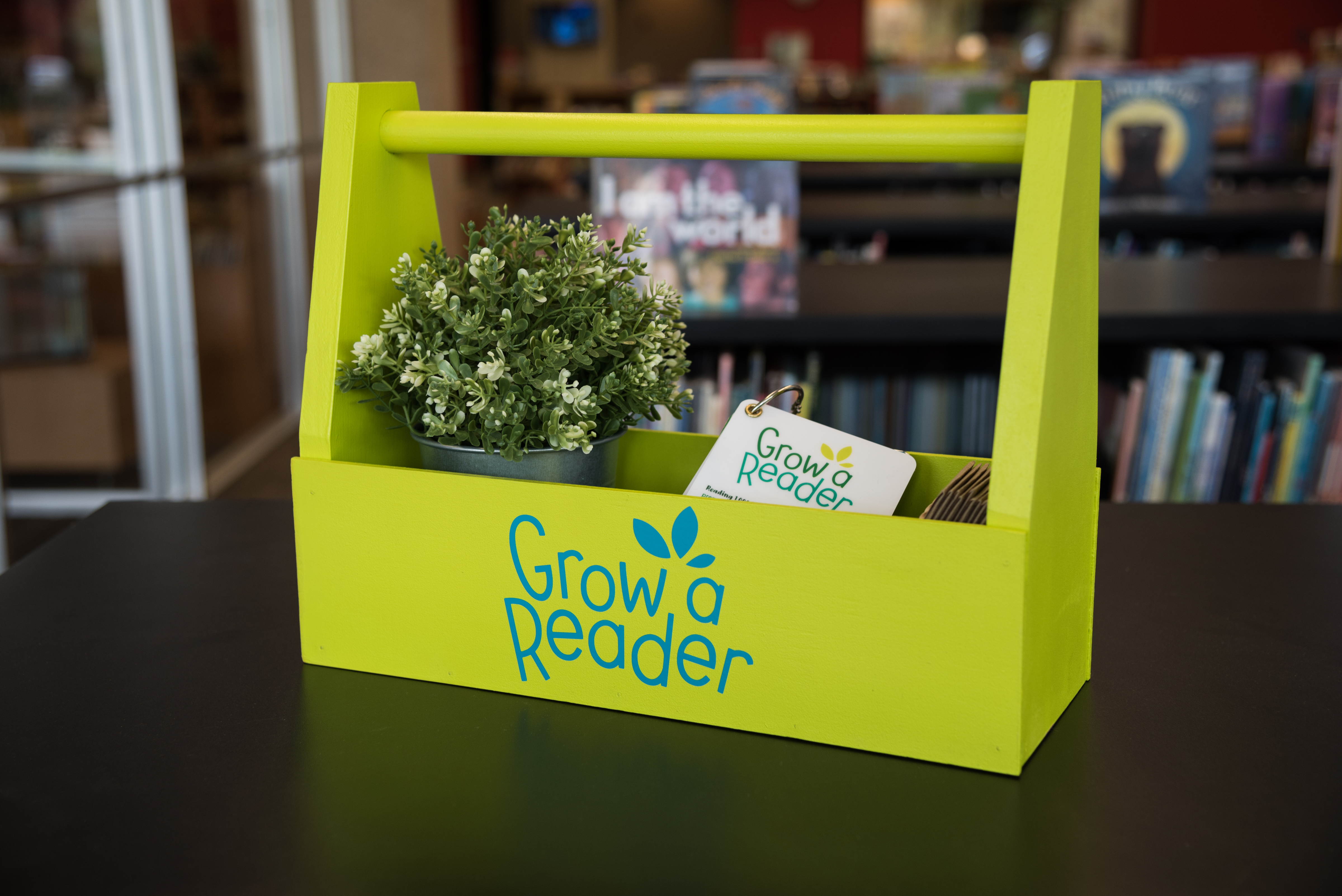 Grow a Reader materials displayed in a wooden box with a plant