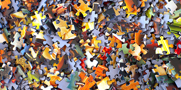 A messy pile of jumbled puzzle pieces with mainly orange, red, and yellow tones.