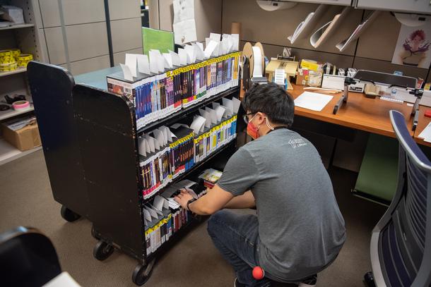 Vince prepares a cart of new materials before they are ready for library shelves