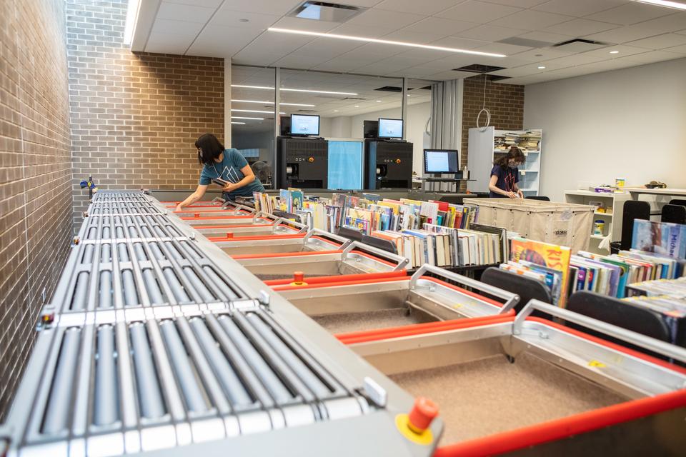 The conveyor of the automated materials handler and book carts in the workroom.