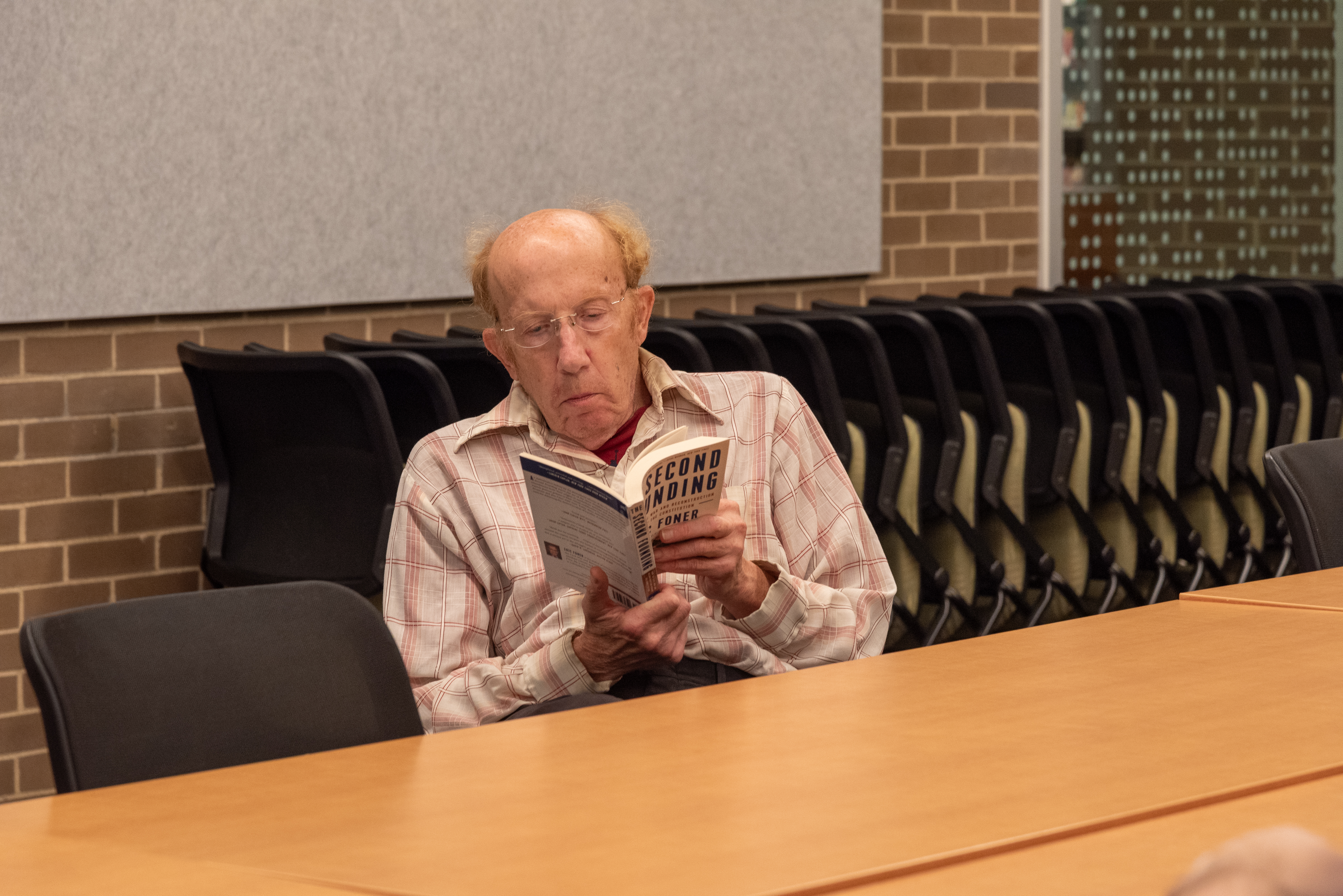 older man seated while holding open a book. older man seated while holding open a book.