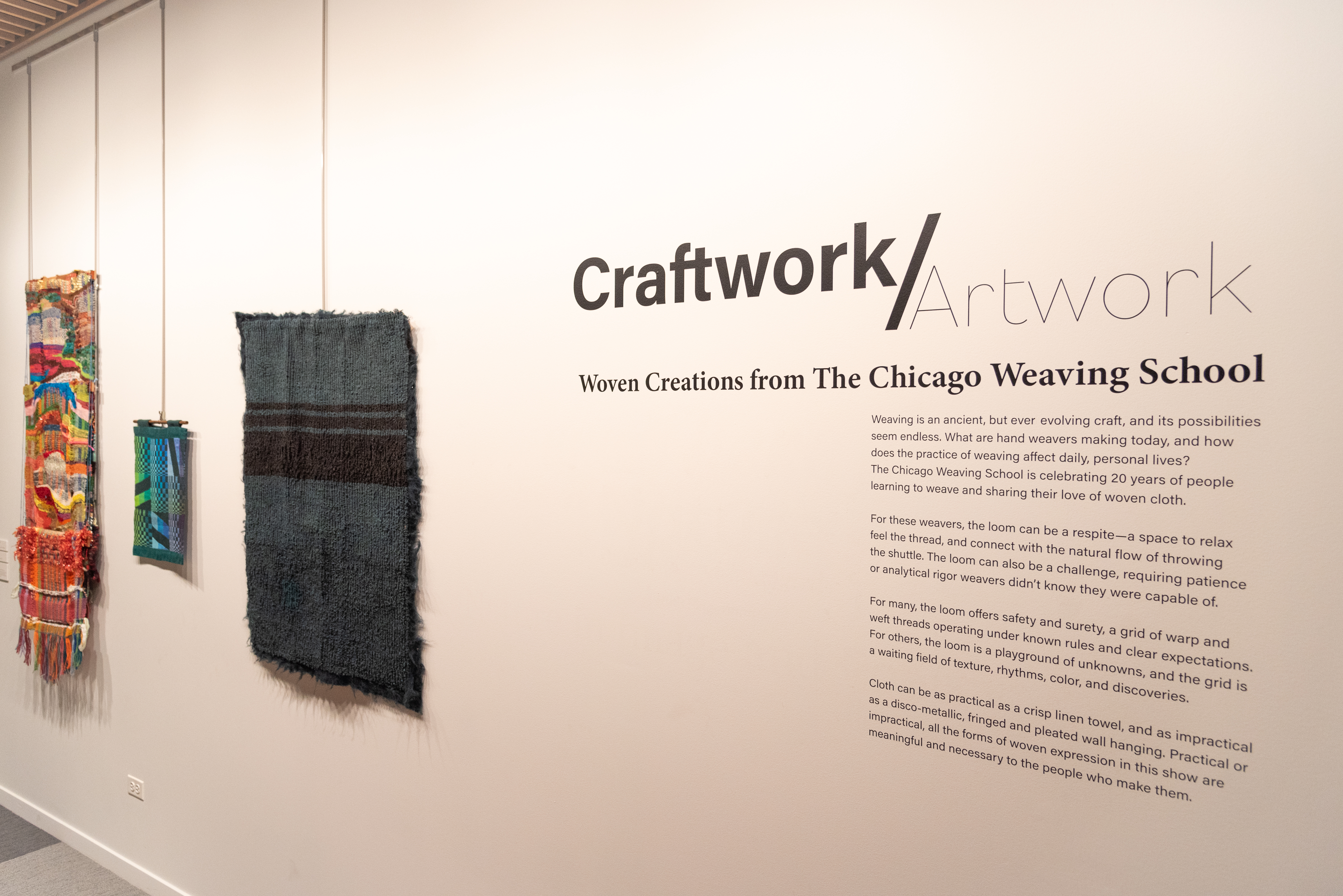Weaving pieces displayed on a wall. Text reads, "Craftwork/artwork."