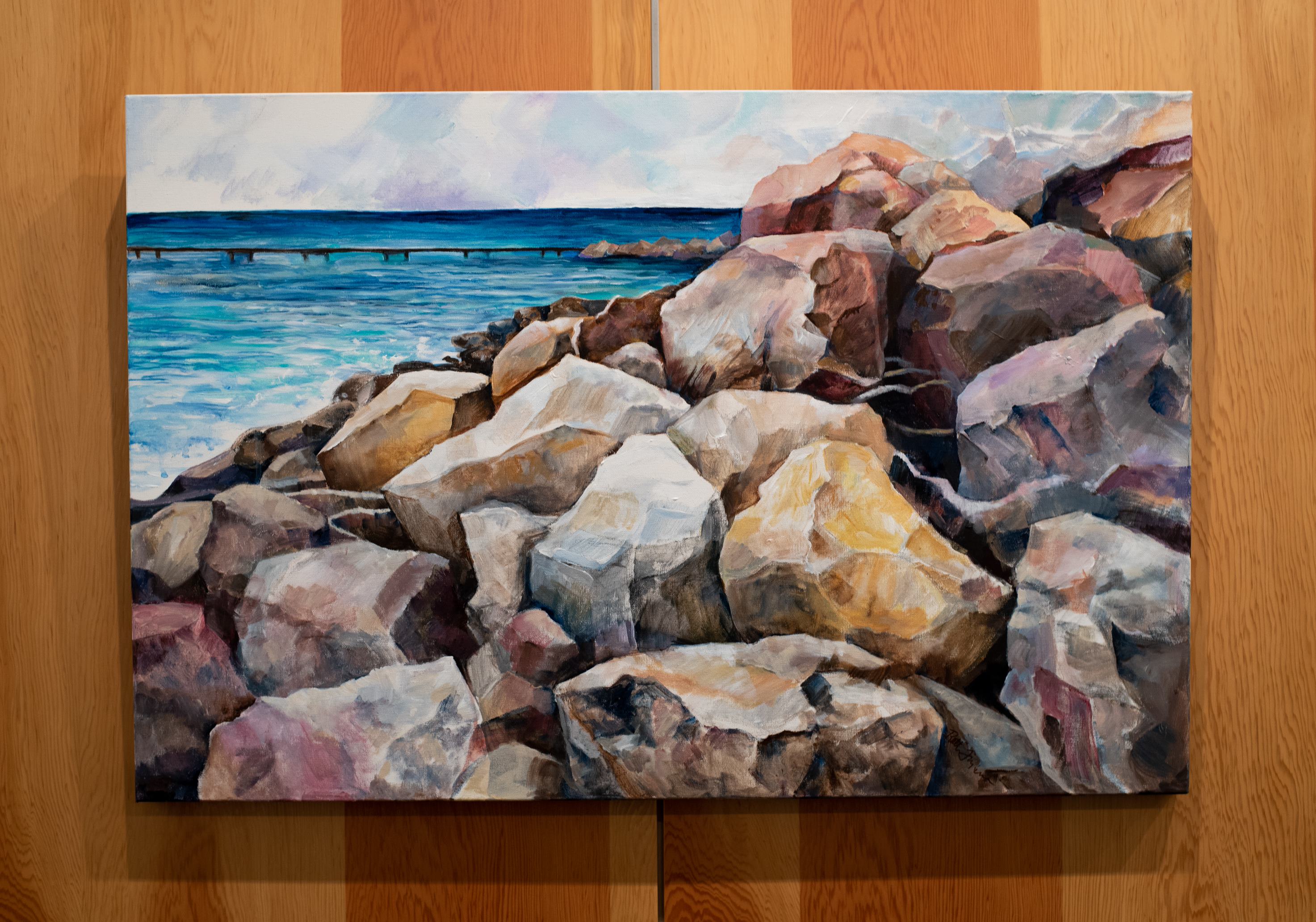 A painting of rocks along the lakeshore