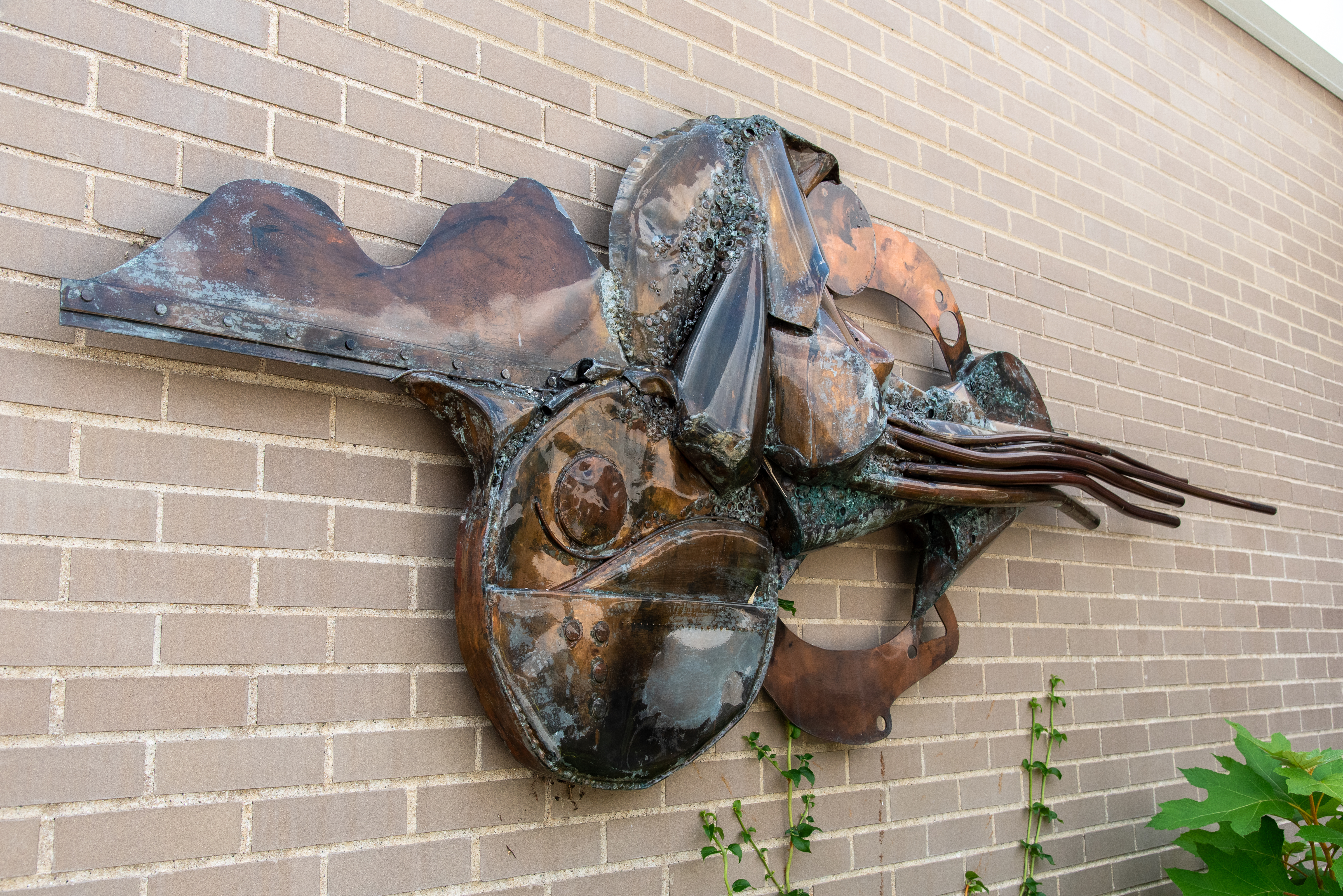 metal sculpture mounted on brick wall