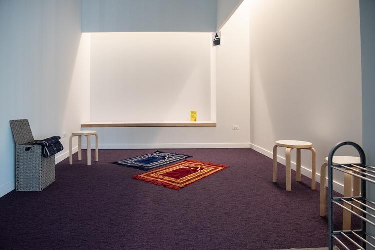 A room with prayer rugs and stool seating