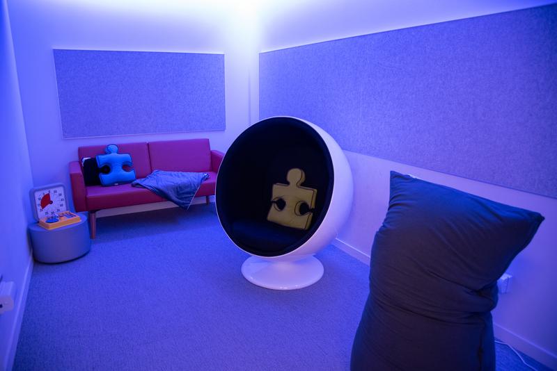Photo of a room with dim lighting, comfortable seats, and calming items like pillows.