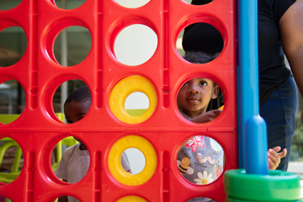 A young patron looks through one of the holes in the giant red Connect 4 on the North courtyard.