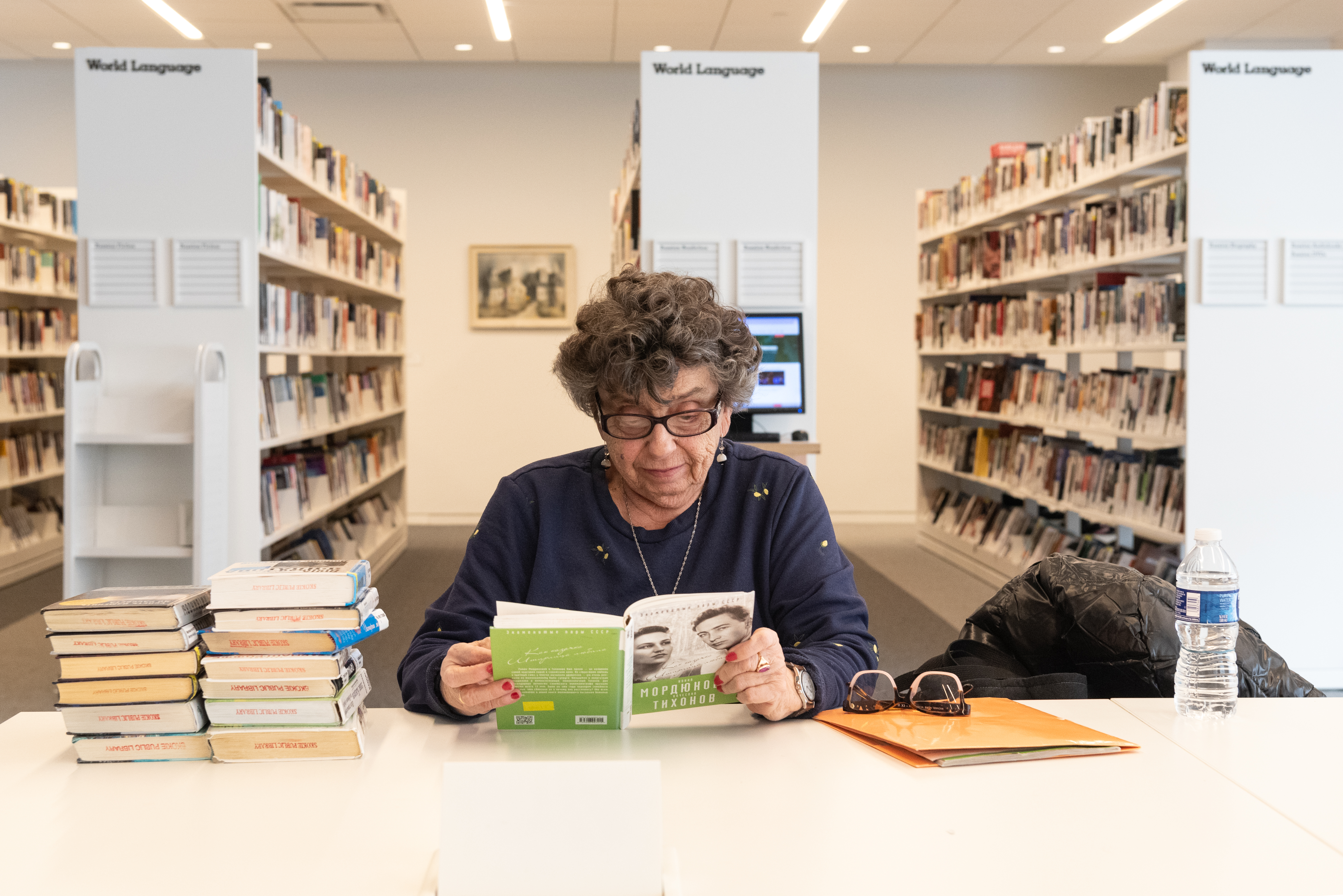 an older woman is looking down at a book in Russian. an older woman is looking down at a book in Russian.