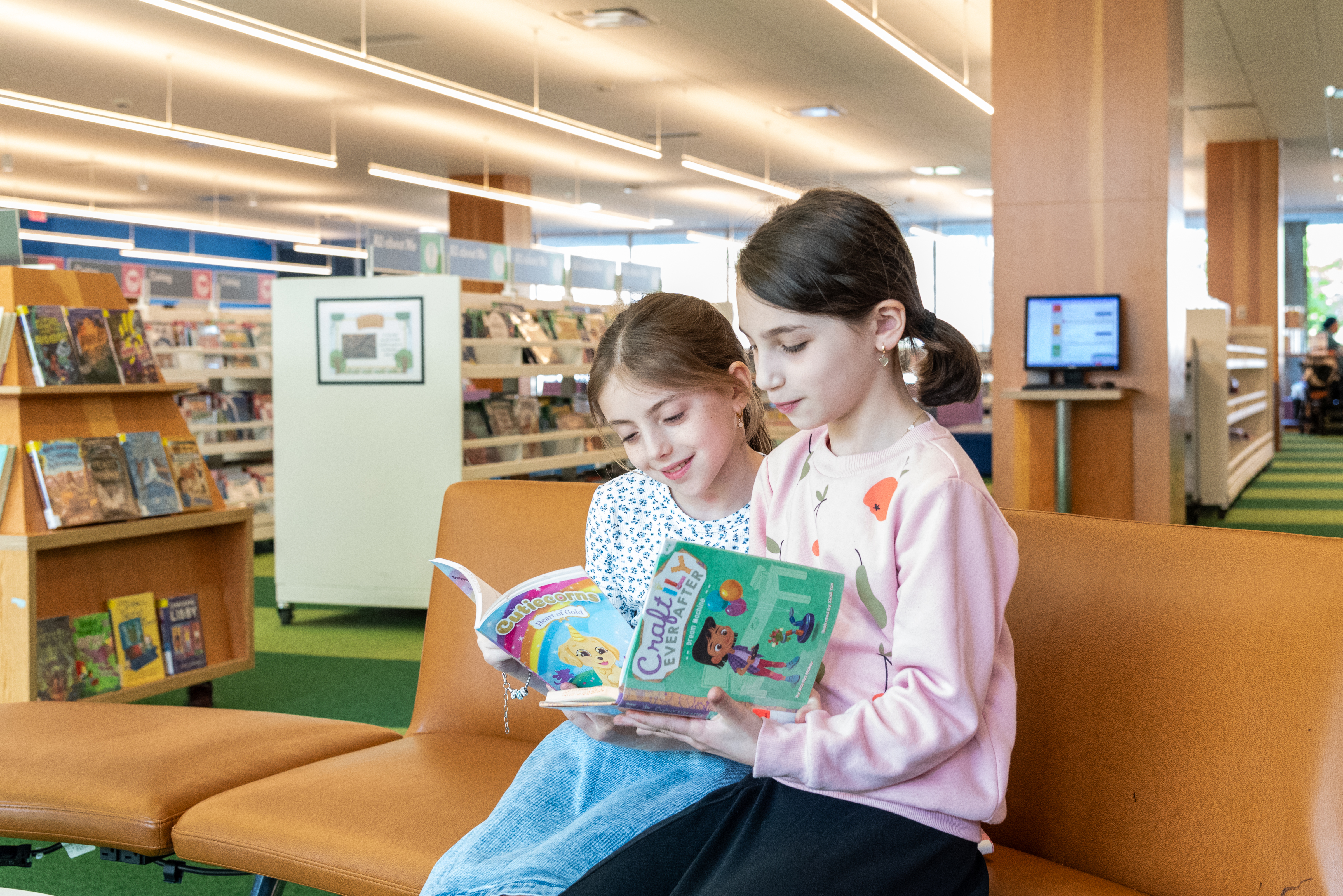 two young girls seated and reading books two young girls seated and reading books