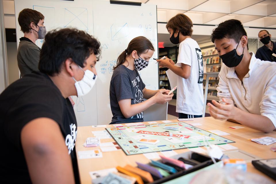 Teens play Monopoly, look at their phone and chat with staff in the Teen Room.