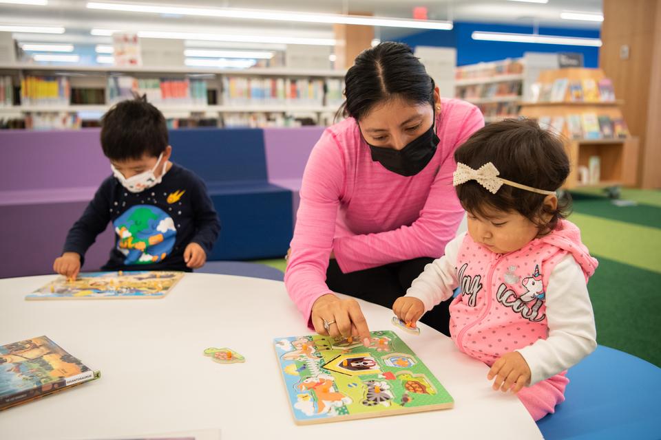 Children and their caregiver play with puzzles in the Kids Room.
