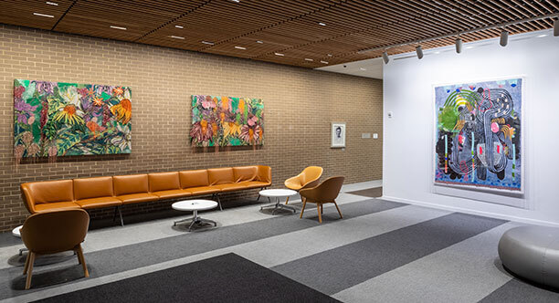 Colorful multimedia art works hang on a brick wall above a brown leather sofa. Colorful multimedia art works hang on a brick wall above a brown leather sofa.
