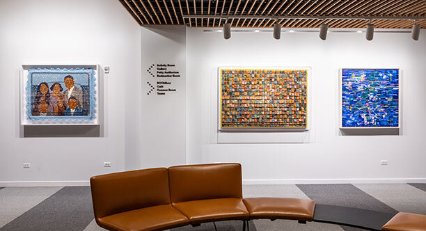 Three multimedia art works hang on a white wall above a brown leather seat Three multimedia art works hang on a white wall above a brown leather seat