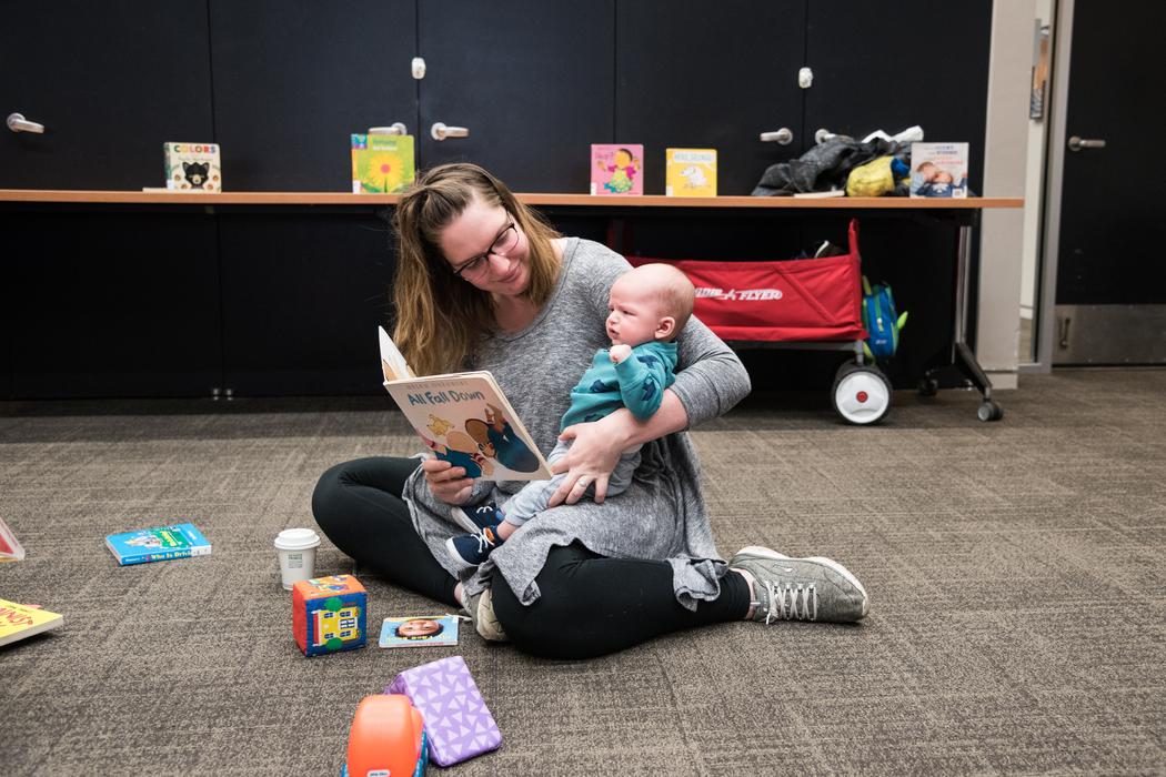 A mother reads a board book to her baby