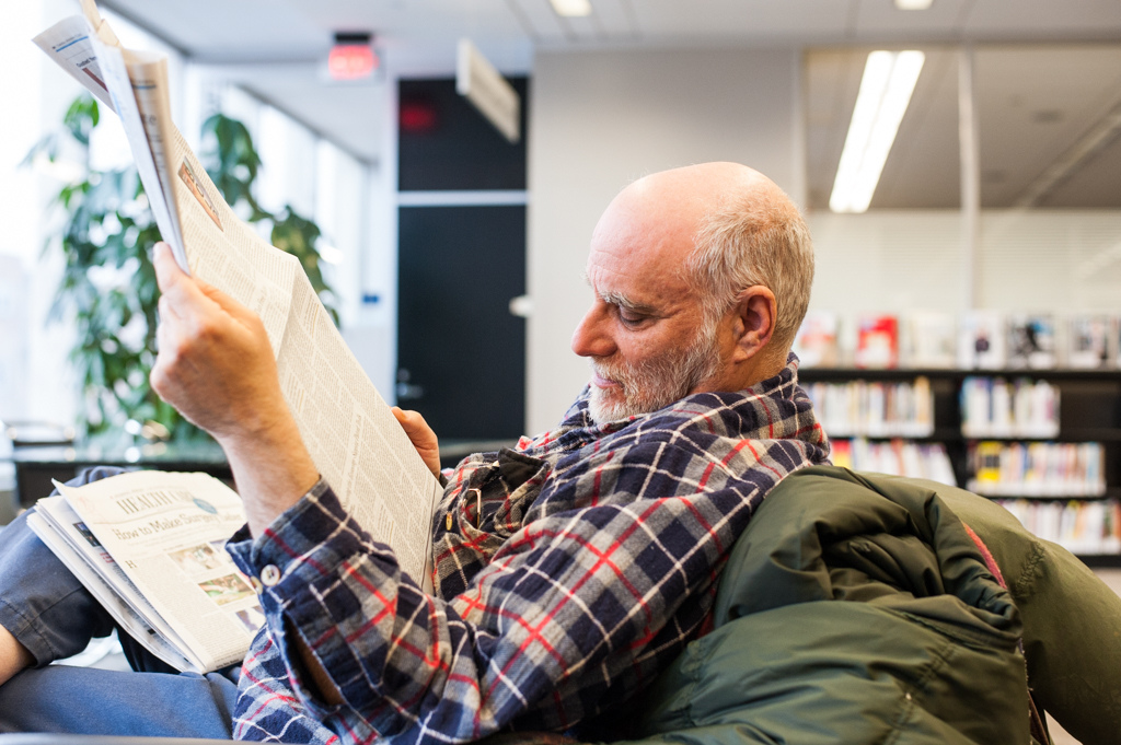 Photo of a patron relaxing in the library with a newspaper
