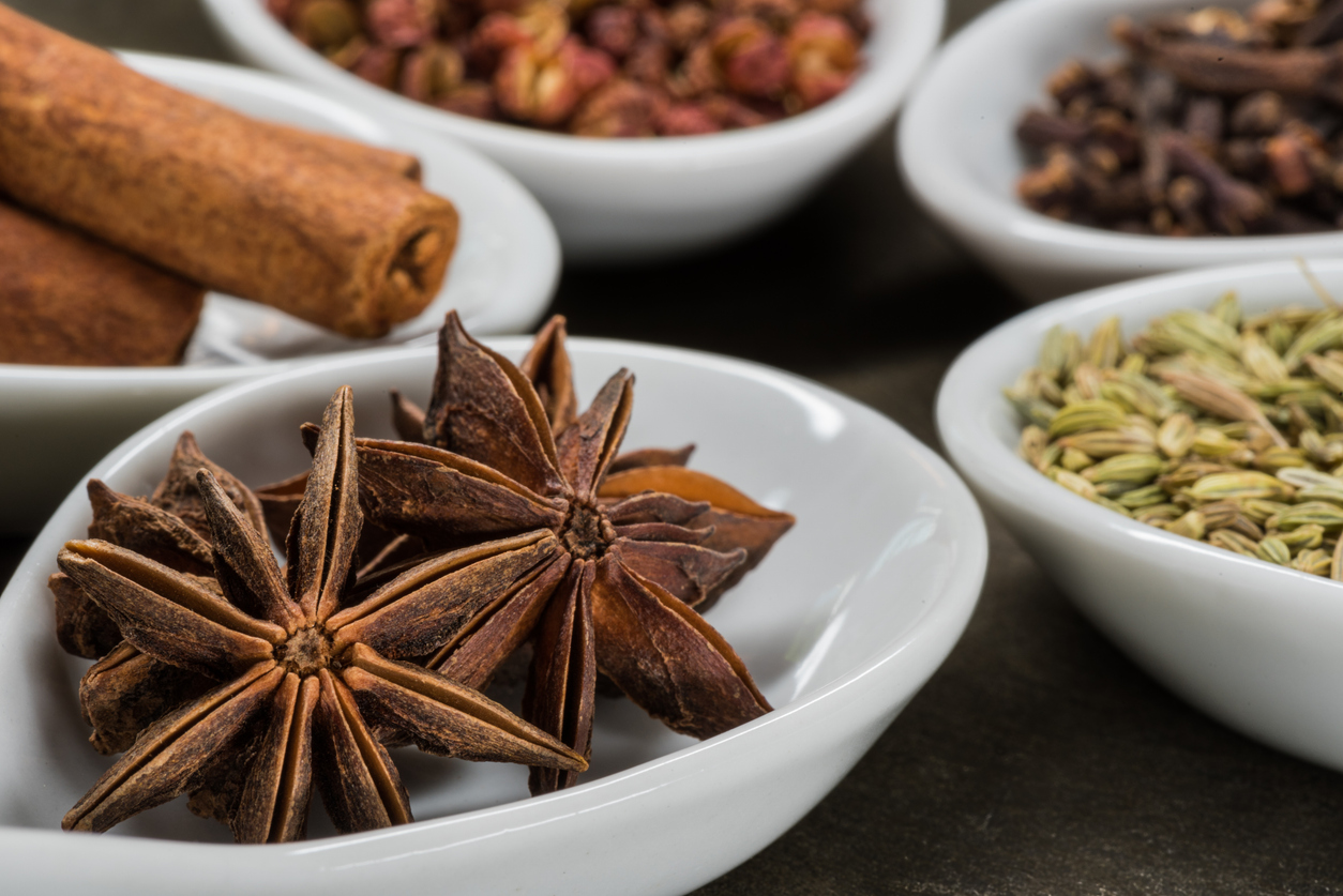Star Anise and Five Spice in White Spoons with anise in foreground Star Anise and Five Spice in White Spoons with anise in foreground