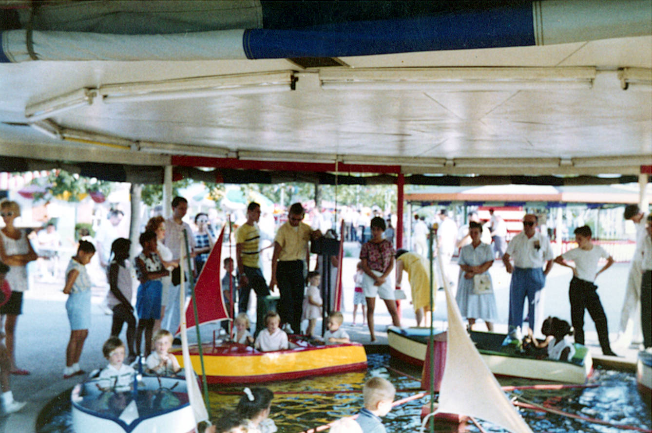 children riding mini-boats ride while adults and other children watch. children riding mini-boats ride while adults and other children watch.